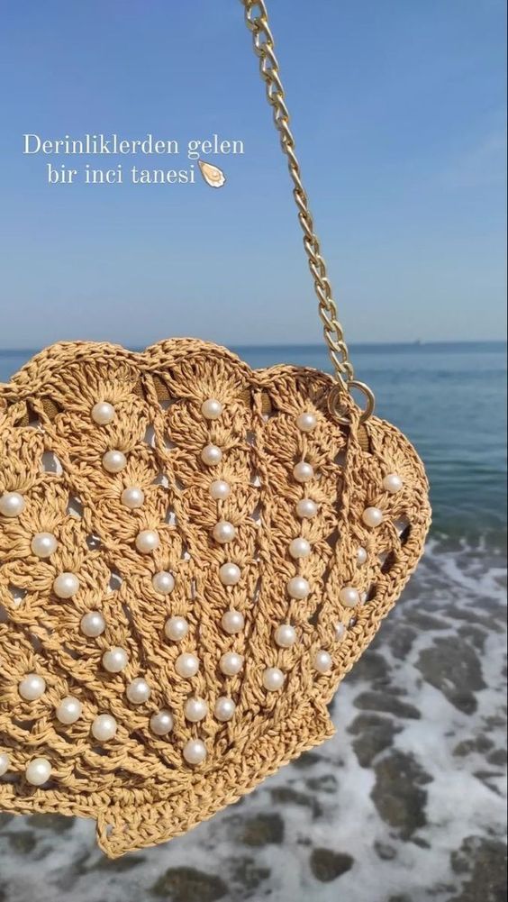 a close up of a handbag on a chain near the ocean with water in the background