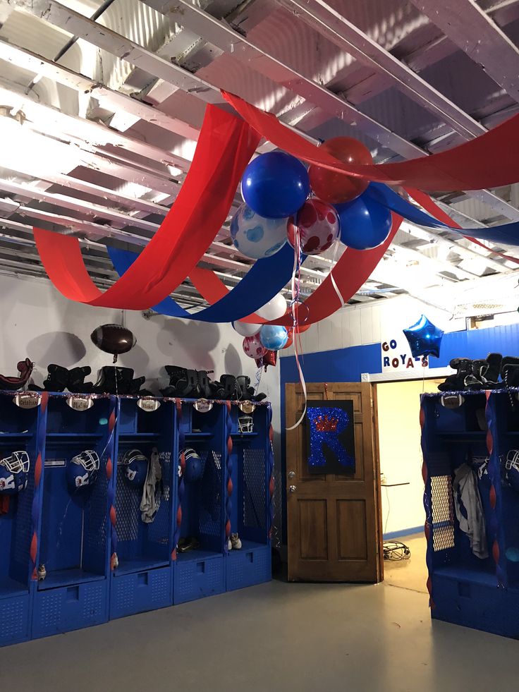 a room filled with blue lockers and red, white and blue balloons hanging from the ceiling