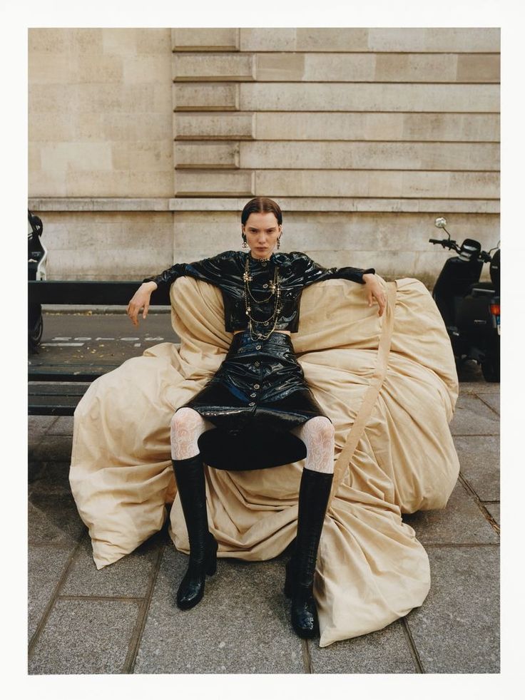 a man sitting on top of a giant couch covered in cloths and wearing black boots