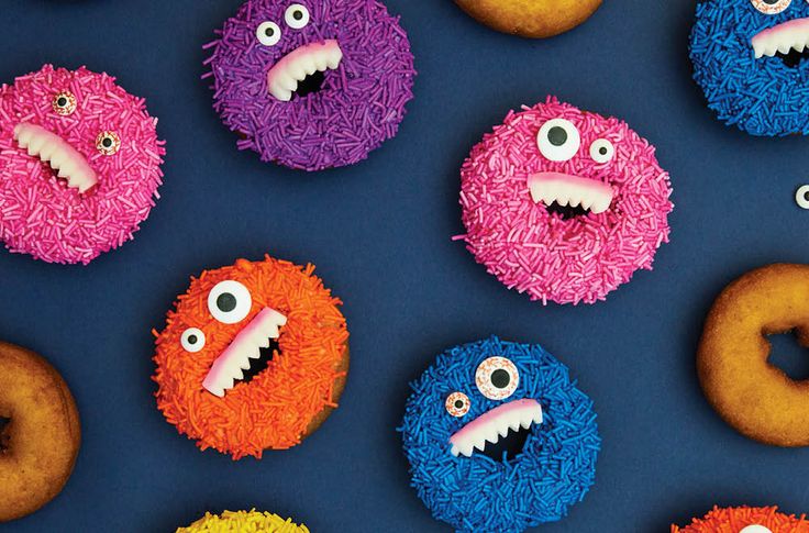 several donuts with different colored frosting and decorated like monster faces are arranged on a blue surface