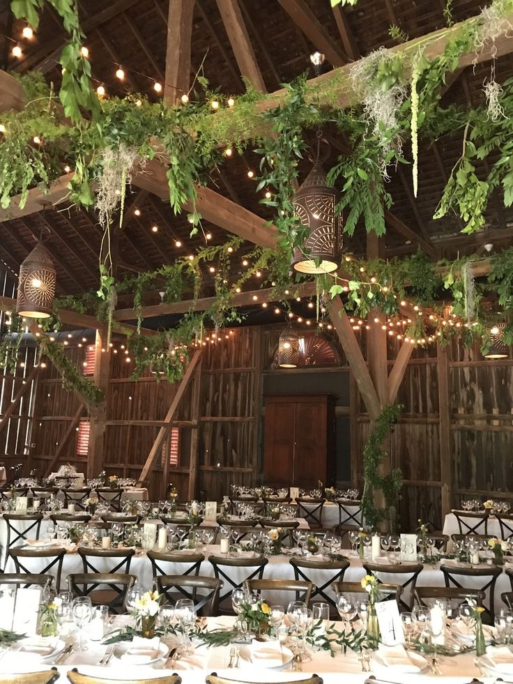 the inside of a barn with tables and chairs set up for an elegant wedding reception