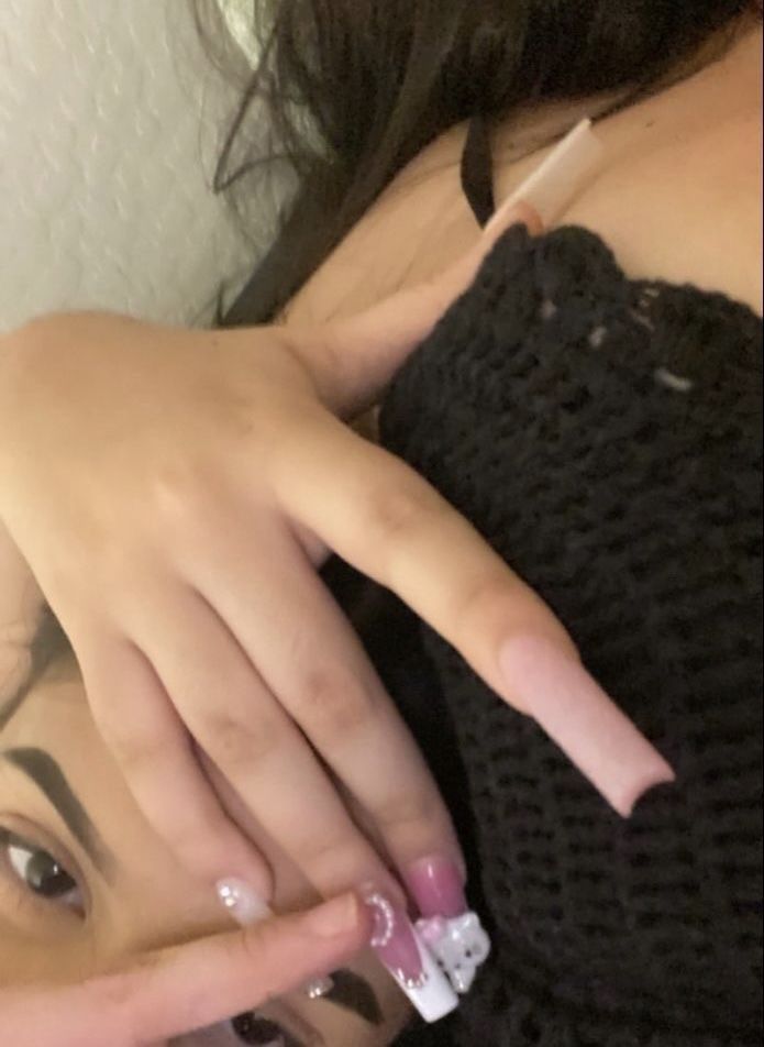 a woman with long nails holding her hand up to her face