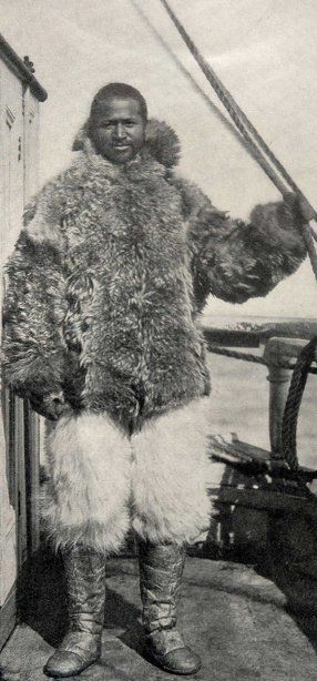 an old photo of a man dressed in fur and boots standing on the deck of a ship