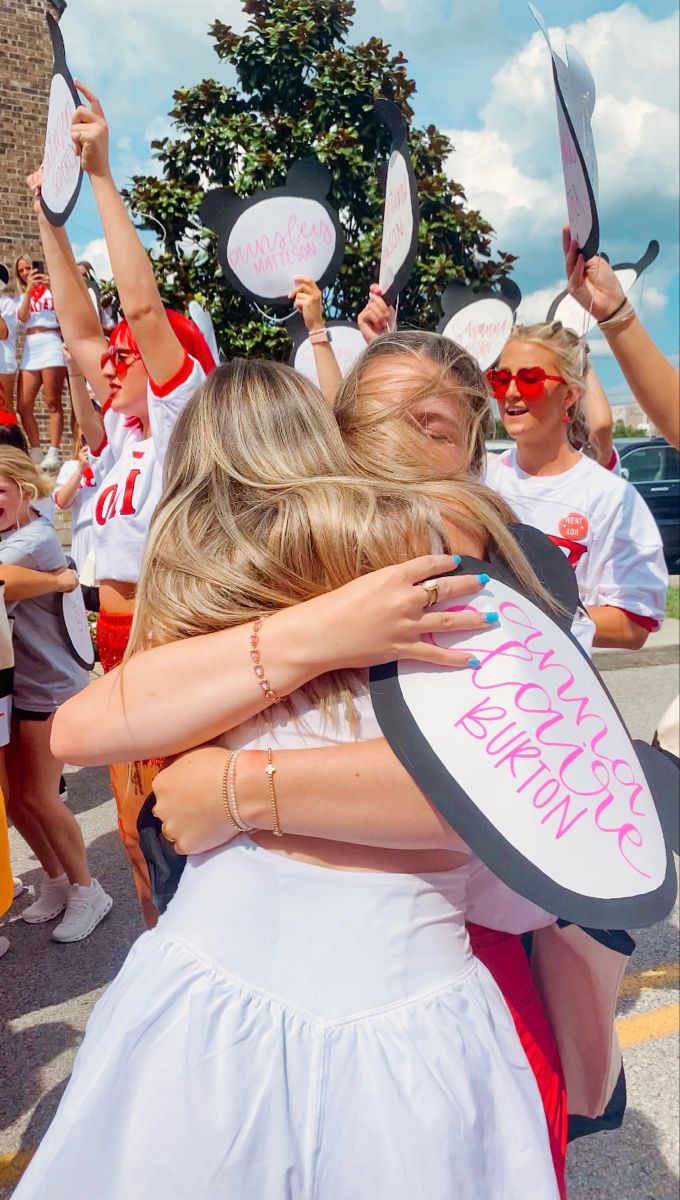 two girls hugging each other in front of a group of people with signs on their heads