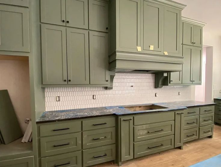 a kitchen with green cabinets and marble counter tops