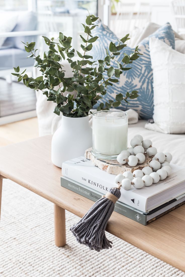 a table topped with books and a vase filled with flowers next to a candle on top of a book