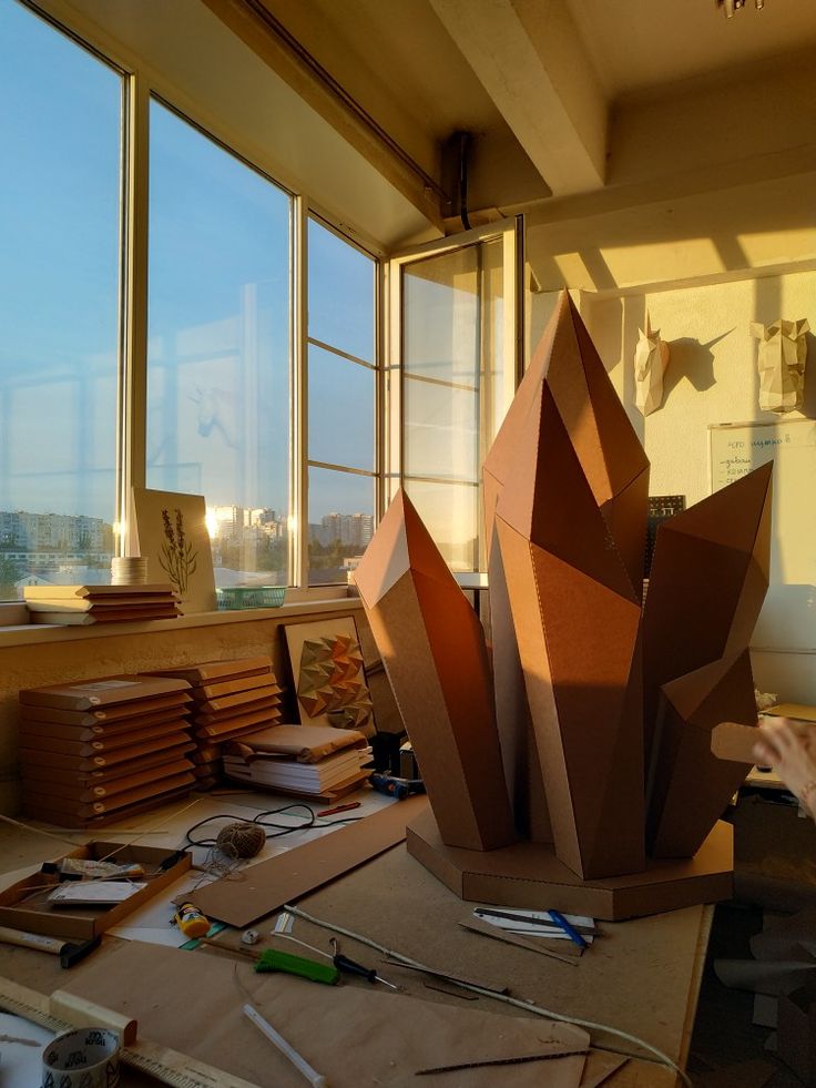 a sculpture made out of cardboard sitting on top of a table next to large windows