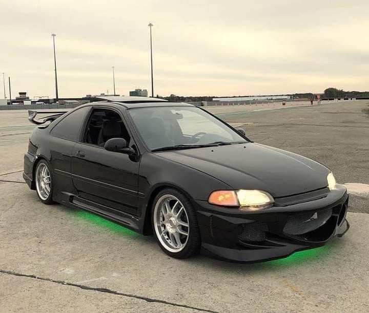 a black car parked on top of an airport tarmac with its hood up and lights on