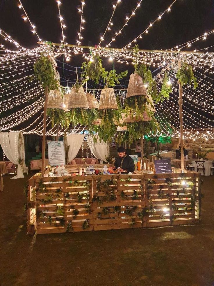 an outdoor market with lots of lights and plants hanging from it's roof over looking the ground