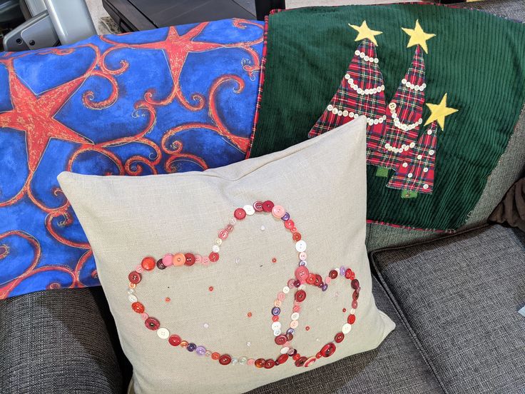 three decorative pillows on a couch with christmas tree and star decorations in the middle one has a peace sign made out of sequinsnized beads