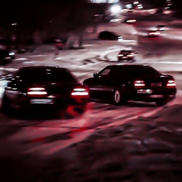 two cars driving down a snowy road at night