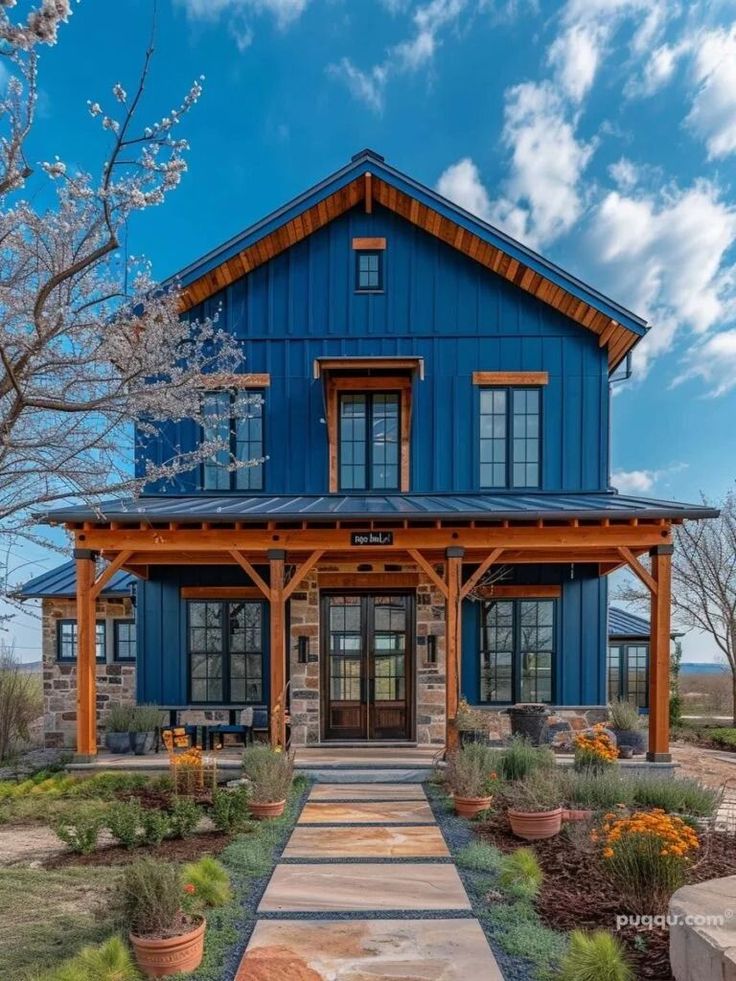 a large blue house sitting on top of a lush green field