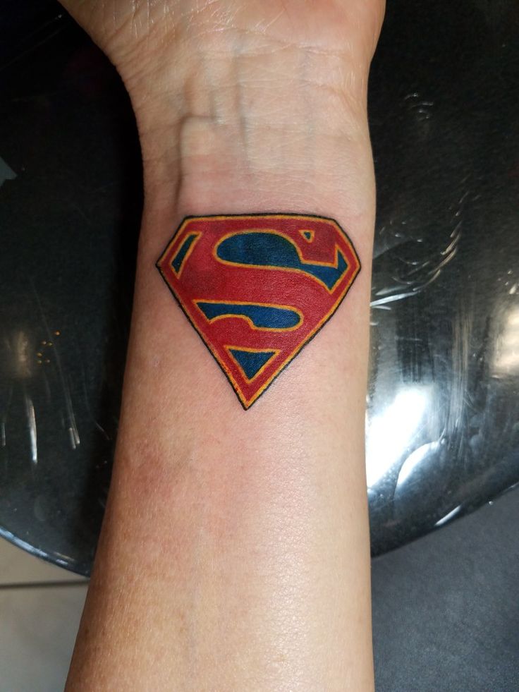 a small superman symbol tattoo on the wrist