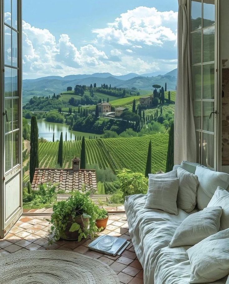 an open window with a view of the countryside and vineyards in front of it