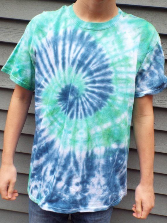 a young boy standing in front of a building wearing a tie - dyed t - shirt