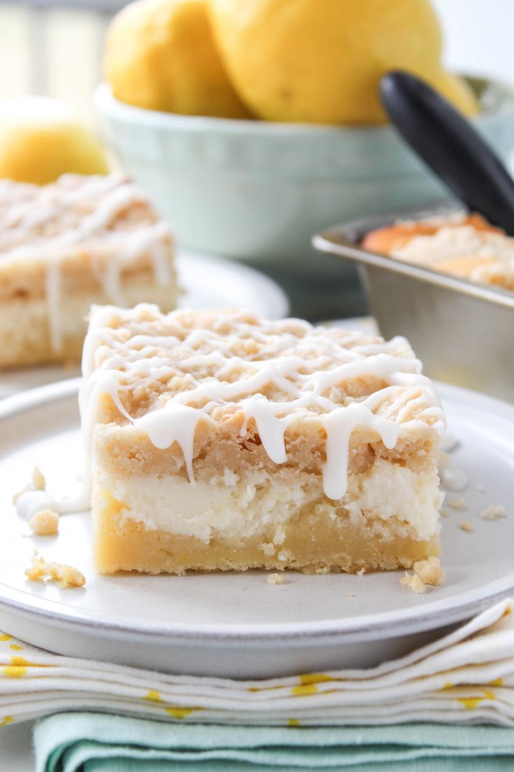 two pieces of lemon cake sitting on top of a white plate next to bowls of lemons