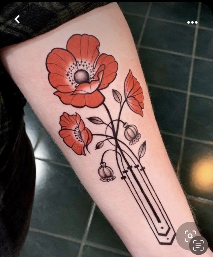 a woman's arm with red flowers on it and a pencil in the middle