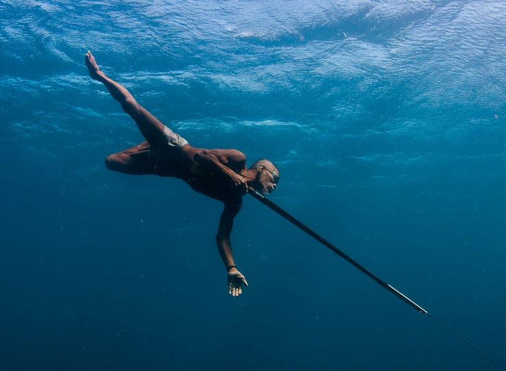 a man swimming in the ocean with a pole attached to his back and feet above water