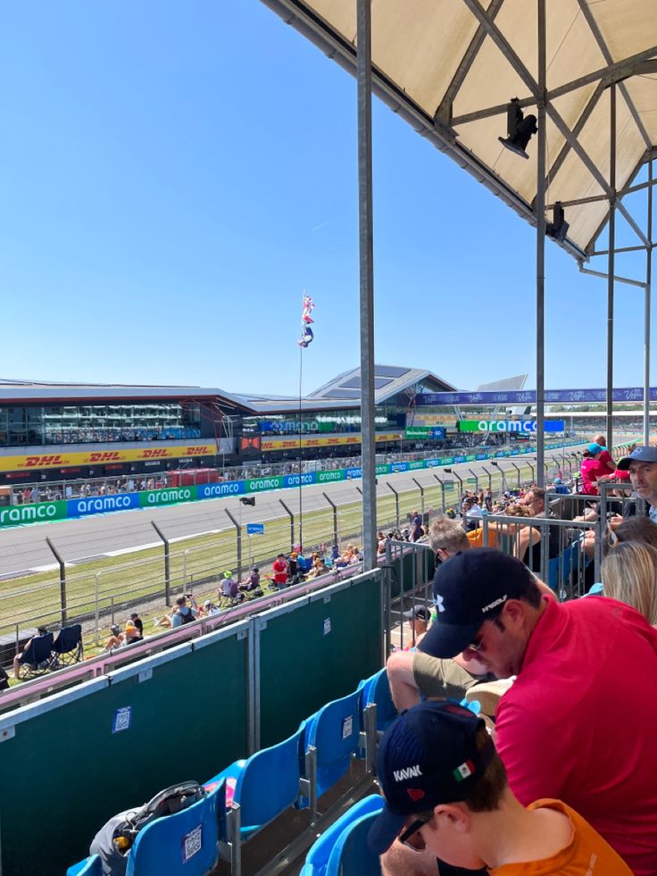 people are sitting in the stands at a race track with their backs turned to the camera