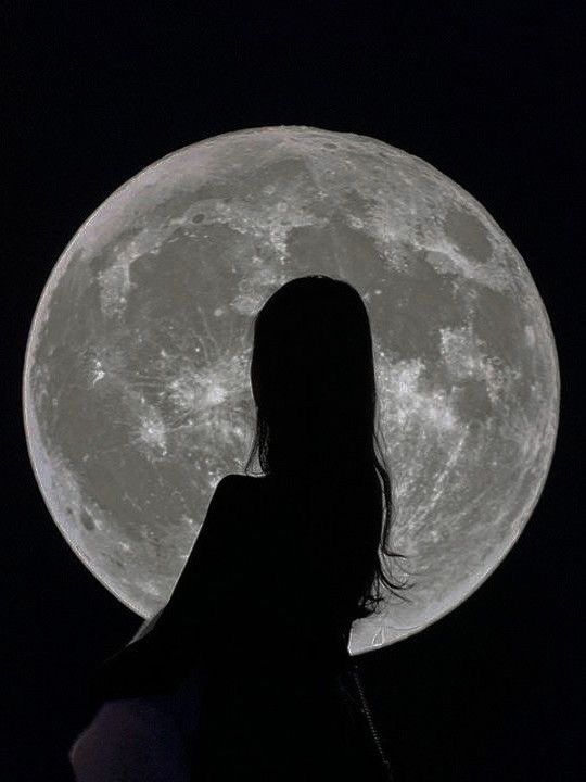 a woman standing in front of a full moon with her back to the camera,