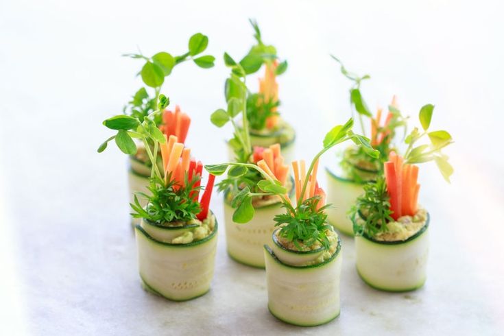 small potted plants with carrots and green leaves in them on a white surface