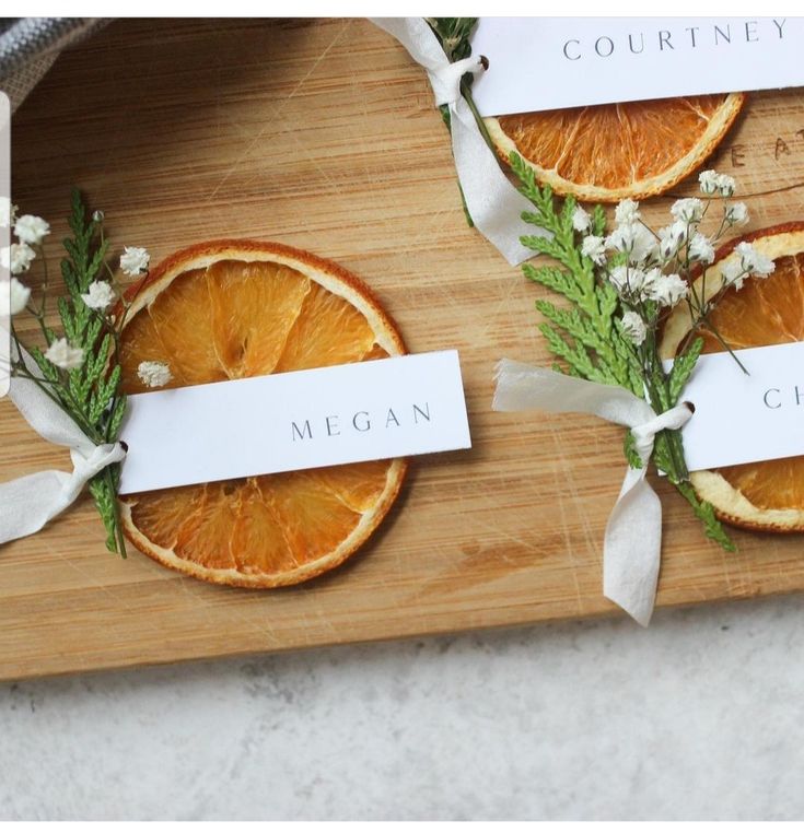 three slices of oranges on a wooden cutting board with white ribbons tied around them