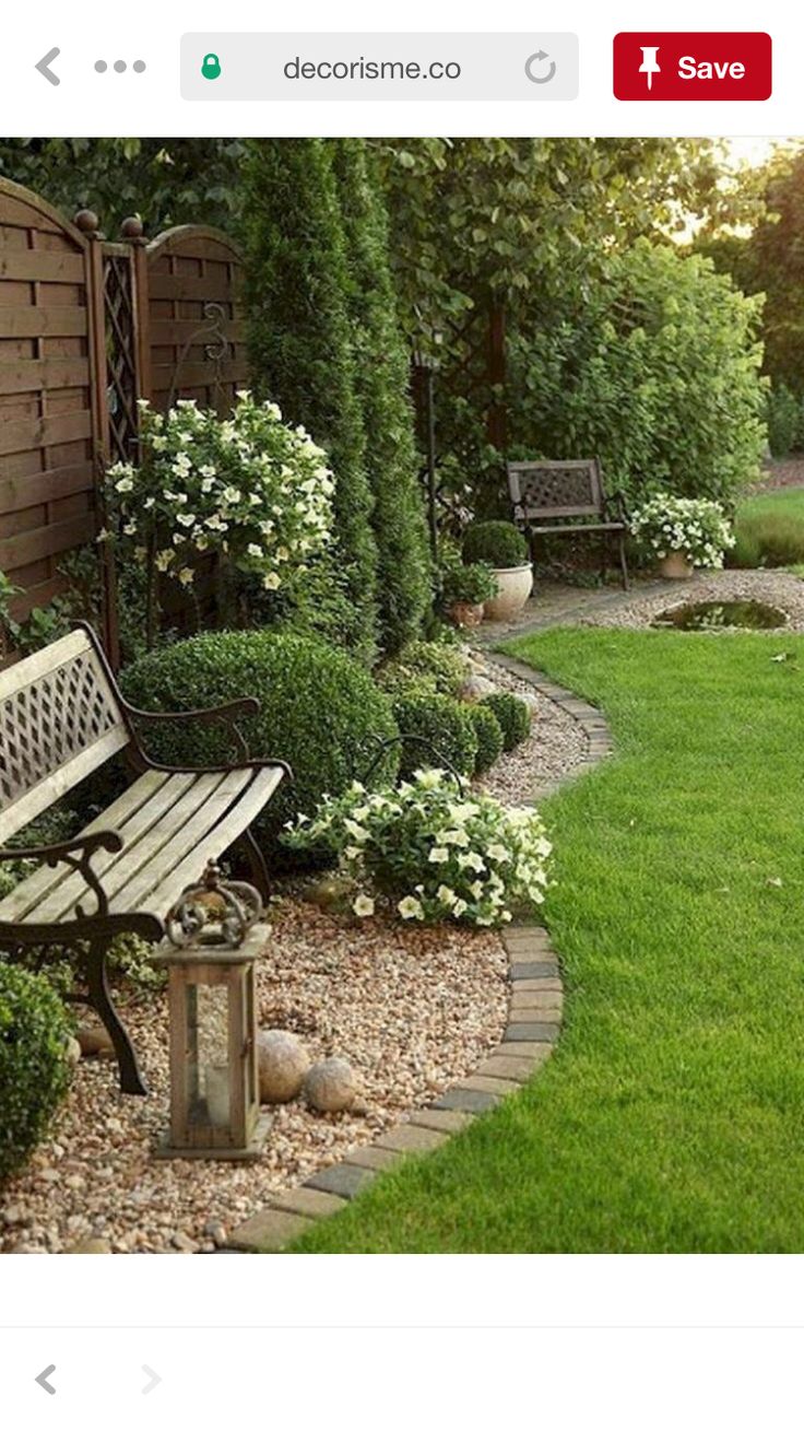 a wooden bench sitting in the middle of a lush green yard next to a stone path