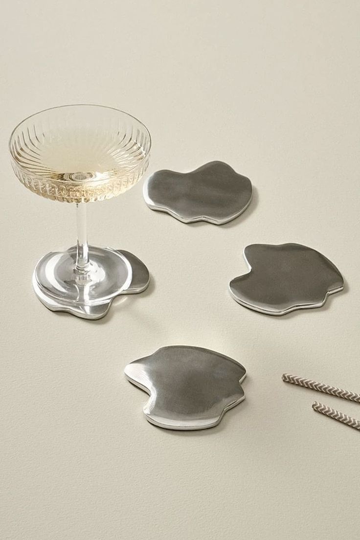 four silver coasters and a wine glass on a table