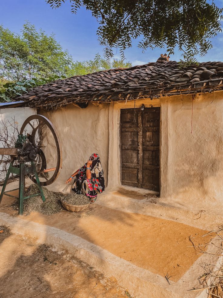 an old adobe house with a wheel on the outside