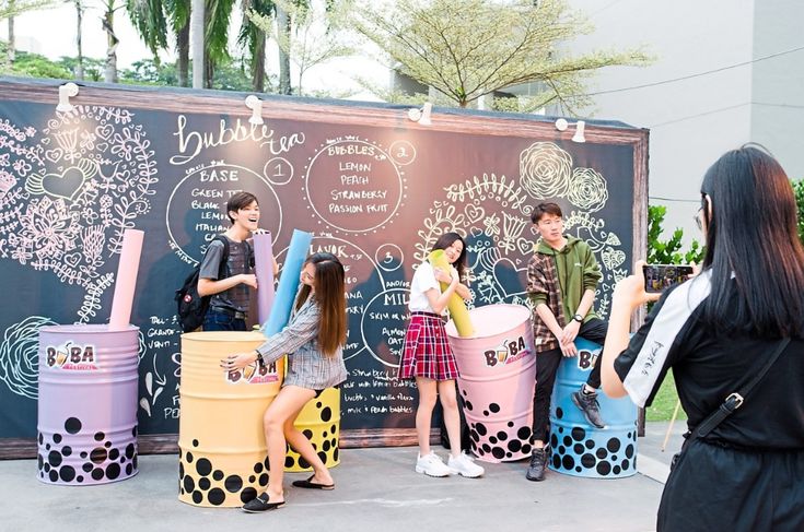 several people standing around ice cream buckets in front of a chalkboard