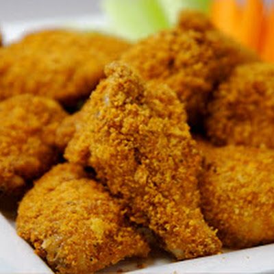 fried chicken on a white plate with carrots and celery in the background