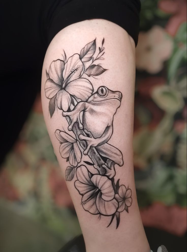 a woman's arm with flowers and a frog tattoo on the left side of her leg