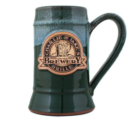 a green beer mug with an emblem on the front and bottom is shown in this image