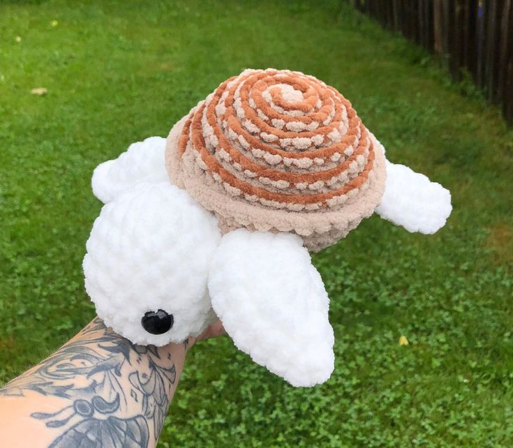 a hand holding a small stuffed animal with a hat on top of it's head