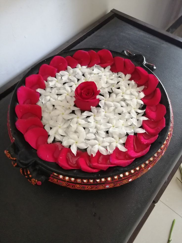 a cake with white and red flowers on it sitting on a black countertop next to a flower pot