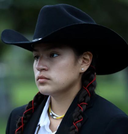 a woman wearing a black cowboy hat and braids