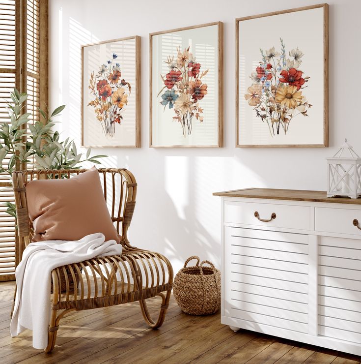 three framed pictures hang on the wall next to a chair and sideboard with a plant in it