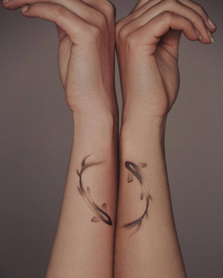 two hands with tattoos on their arms and one has a fish tattoo on it's arm