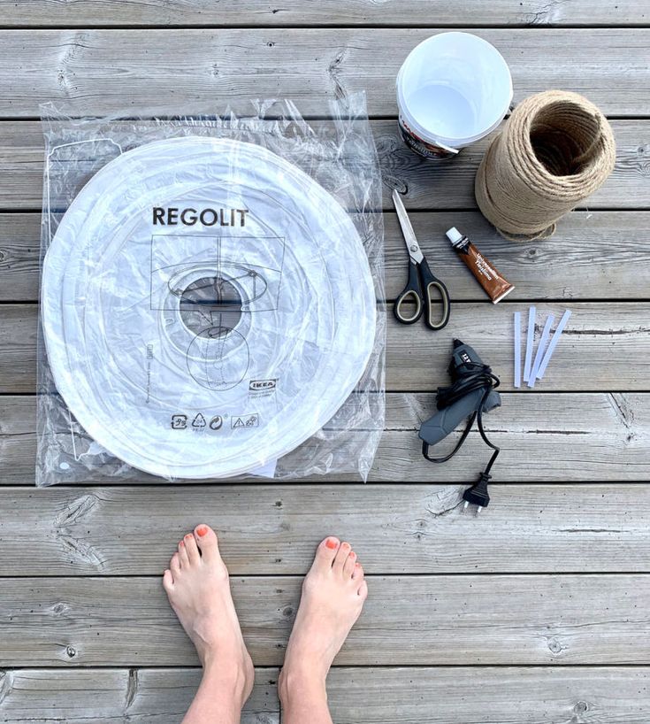 a person standing on a wooden deck with their feet propped up next to some crafting supplies