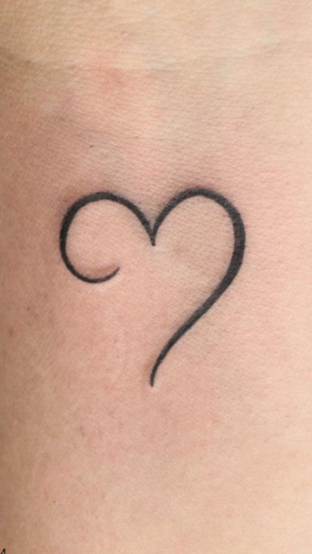 a small heart tattoo on the back of a woman's neck