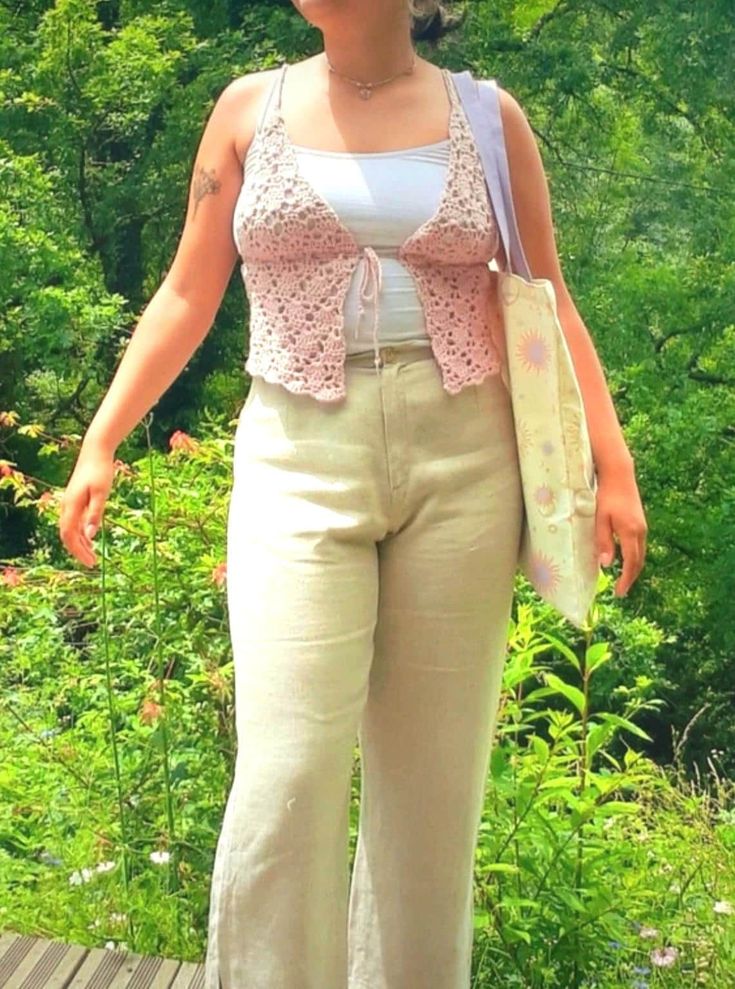 a woman standing on top of a wooden platform in front of trees and bushes with her hands in her pockets