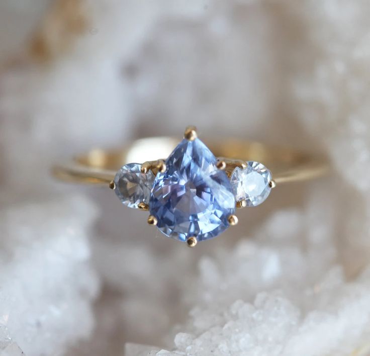 Imagine the prettiest color of the sky, and we have it captured in a form of a ring. Meet Carrie  - a pear blue sapphire ring with lighter blue sapphires on the side. Set in 14k gold, it’s a breath of fresh air on your fingers. NOTE: This design can be also made with other sapphire color shade per request. We offer wid Pear Sapphire Ring, Classic Engagement Ring Solitaire, Ring Inspo, Love Knot Ring, Sapphire Rings, Blue Sapphire Ring, Sapphire Engagement Ring, Blue Sapphire Rings, Sapphire Engagement