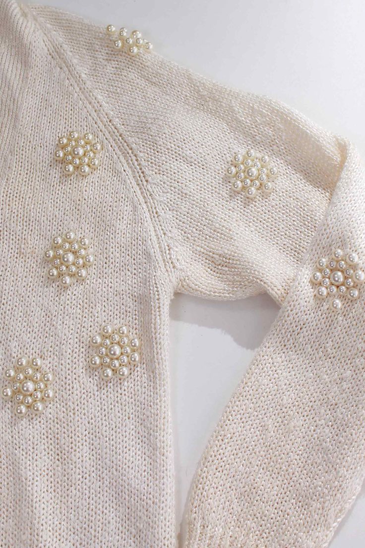 a white sweater with pearls on it