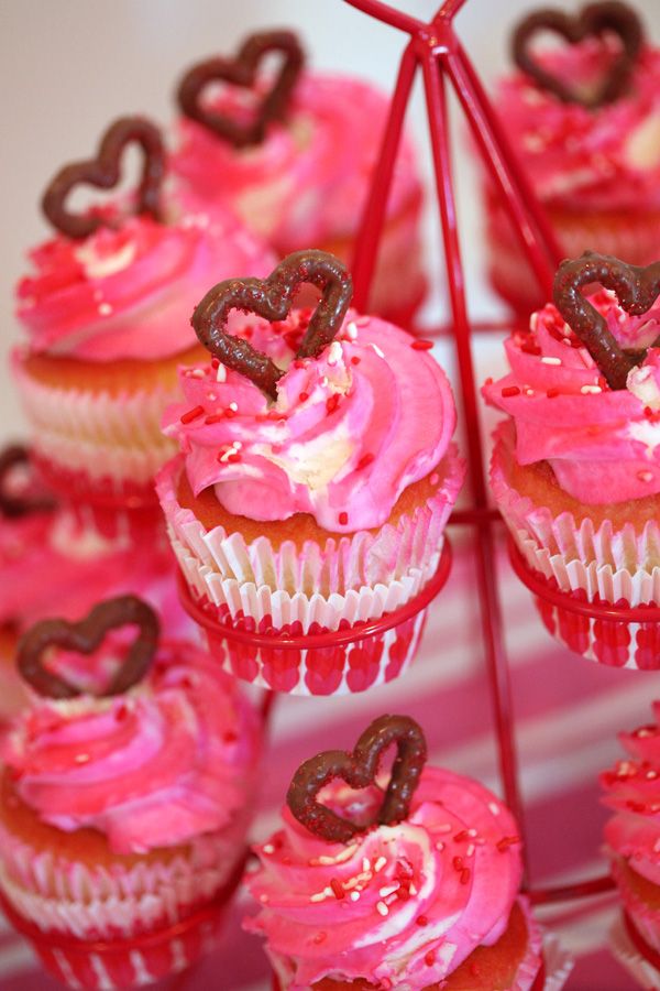 cupcakes with pink frosting and chocolate hearts on top are arranged in a pyramid