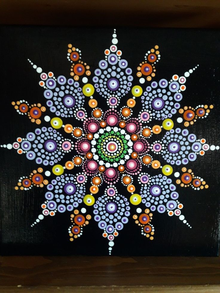 a colorful painting on a black surface with circles and dots in the center, as well as an abstract flower design