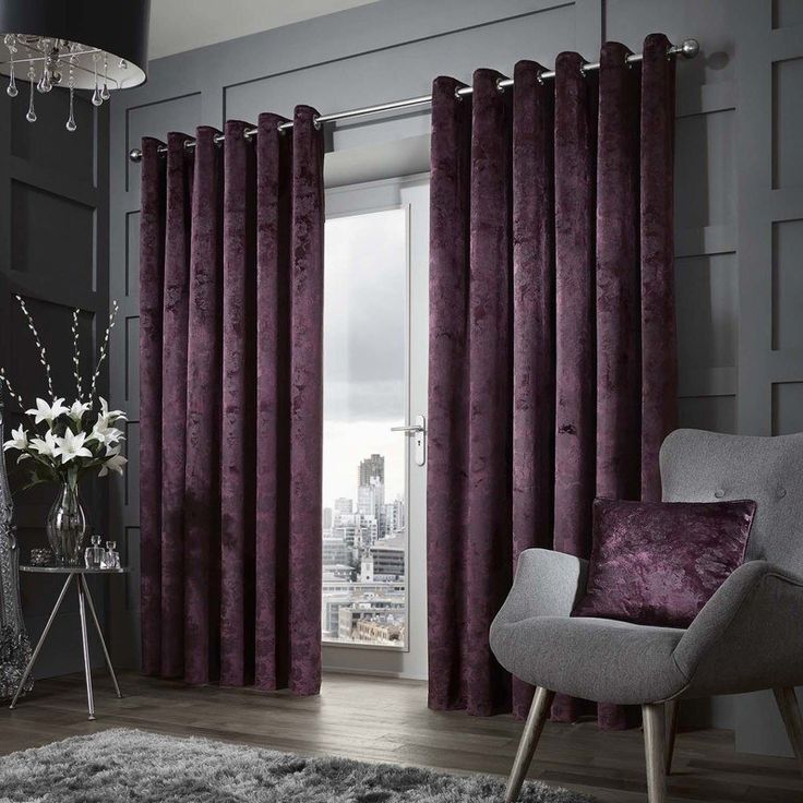 a living room with purple curtains and a chair in front of a window that has cityscape on it