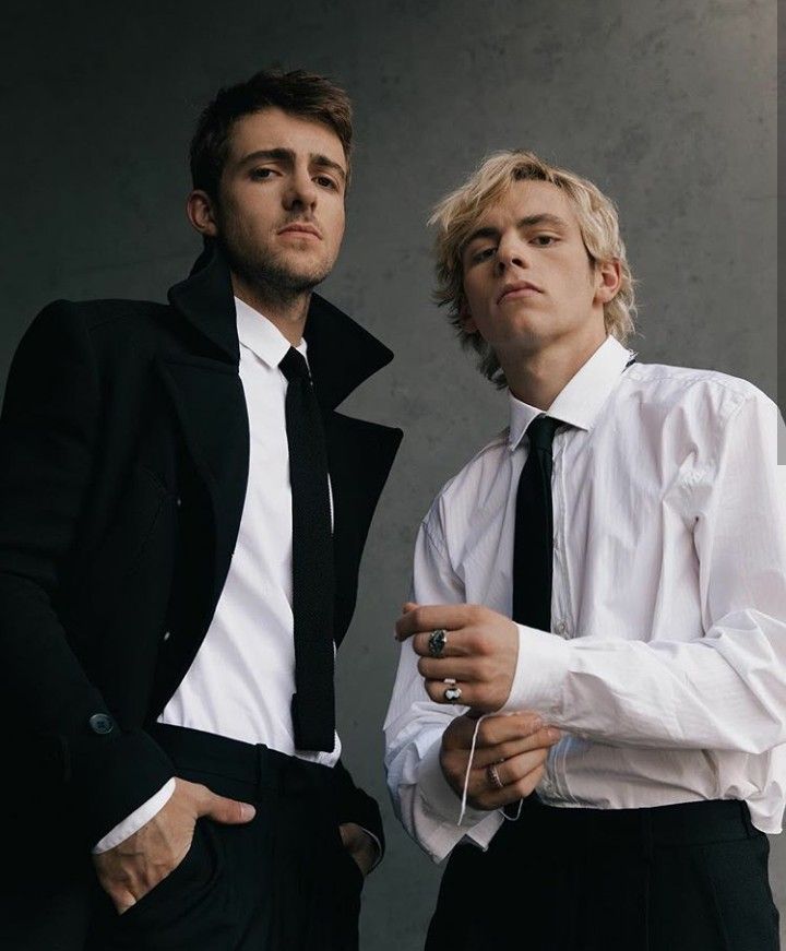 two young men dressed in black and white posing for the camera with their hands on their hips