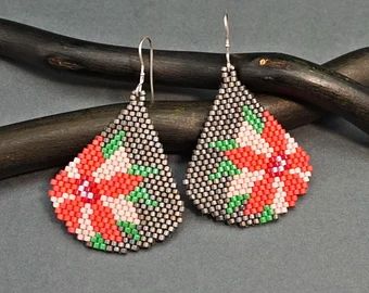 a pair of beaded earrings sitting on top of a piece of wood next to a twig