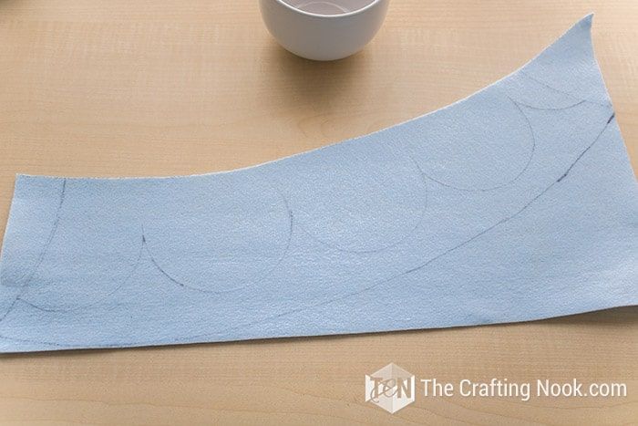 a piece of blue paper sitting on top of a wooden table next to a cup