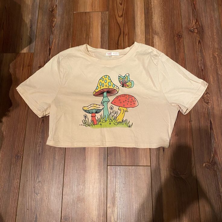 Mushroom Crop Top Tee. Brand New With Tags. Light Cream Color. Size Large. Chest Measures About 19.75”, Length 16.25” Casual Mushroom Print T-shirt For Spring, Mushroom Print Crew Neck Graphic Tee, Mushroom Print Graphic Tee With Crew Neck, Summer Short Sleeve Tops With Mushroom Print, Spring White Tops With Mushroom Print, White Mushroom Print Top For Spring, Spring White Top With Mushroom Print, Cotton Crew Neck Tops With Mushroom Print, Cute Short Sleeve Top With Mushroom Print